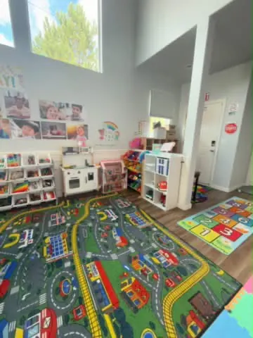 Spacious playroom with hopscotch rug, toy shelves and play kitchen